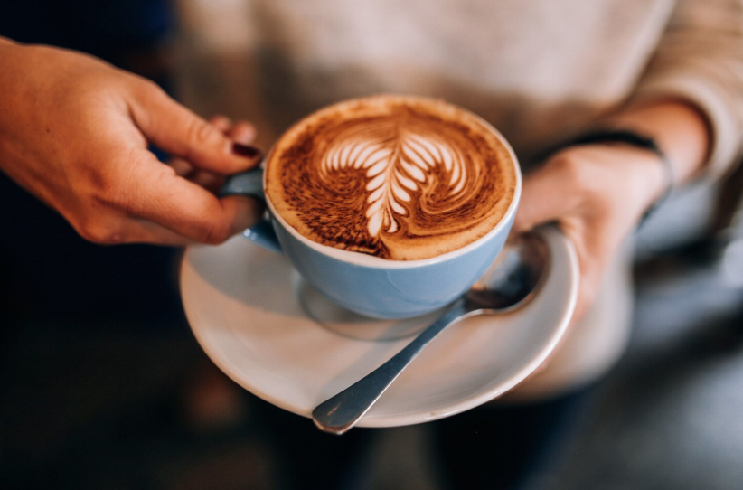 жена държи чаша капучино в близък план