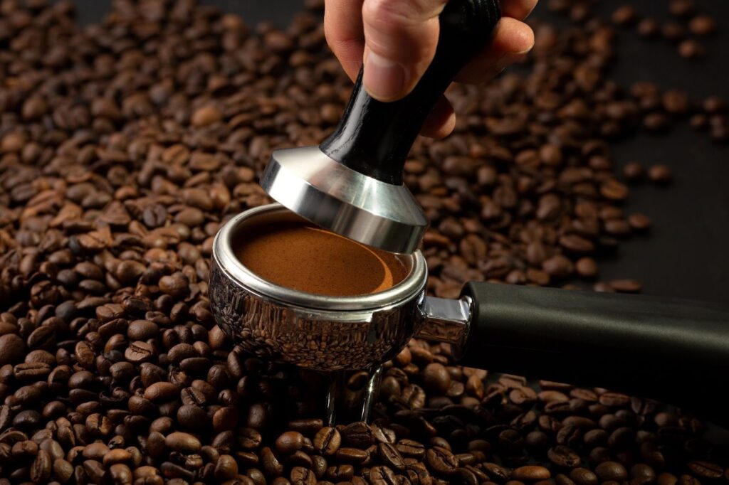 Кафени зърна на заден план и смляно кафе по време на пресоване